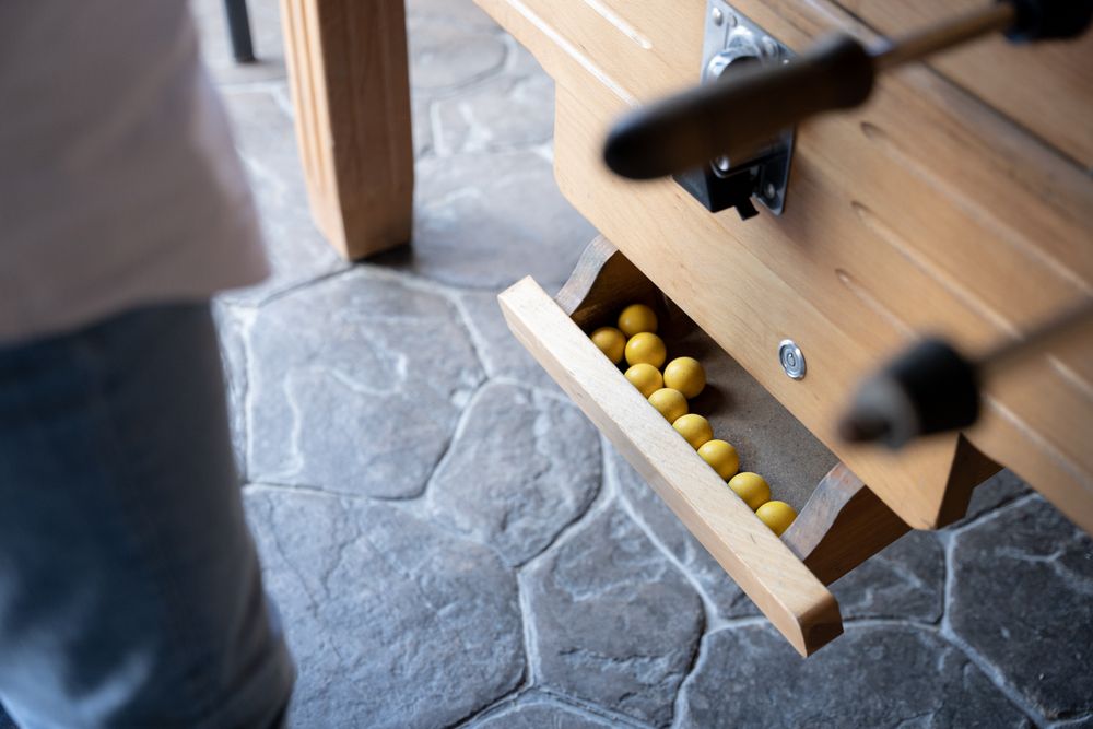 Close up of some yellow table football balls ready to be played in the dispenser