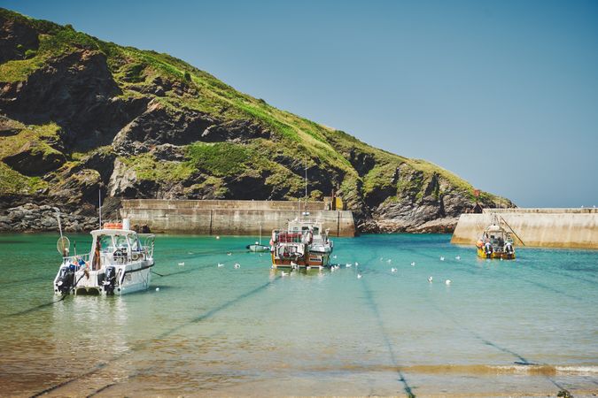 Boats parks in the water overlooked by cliffs