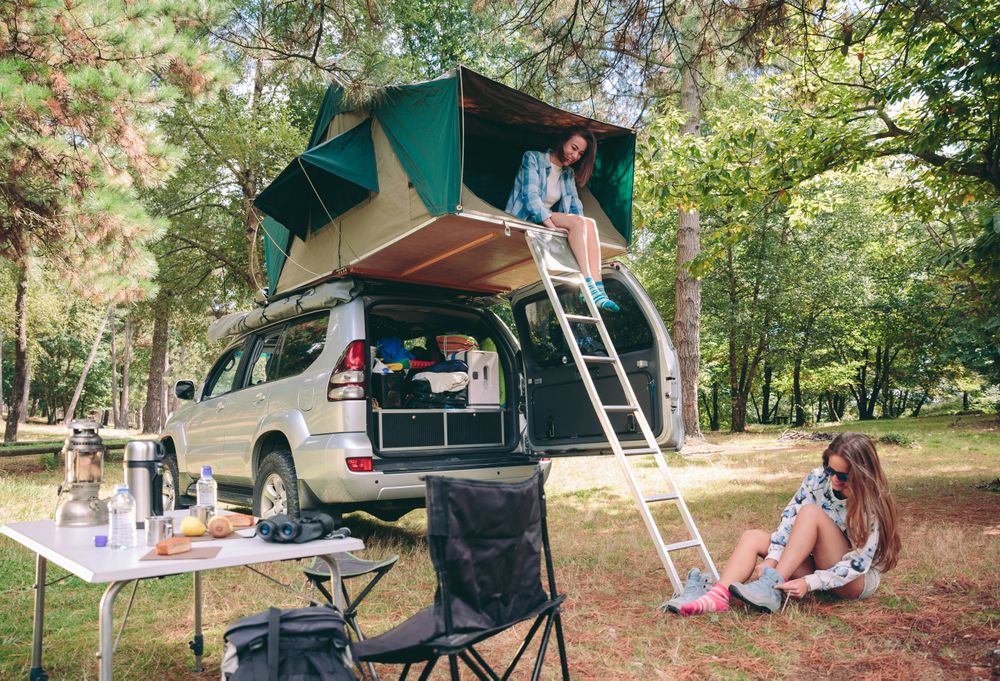 Woman in tent over 4x4 putting on hiking boots