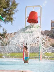 Happy boy playing with splashing waterfall from bucket