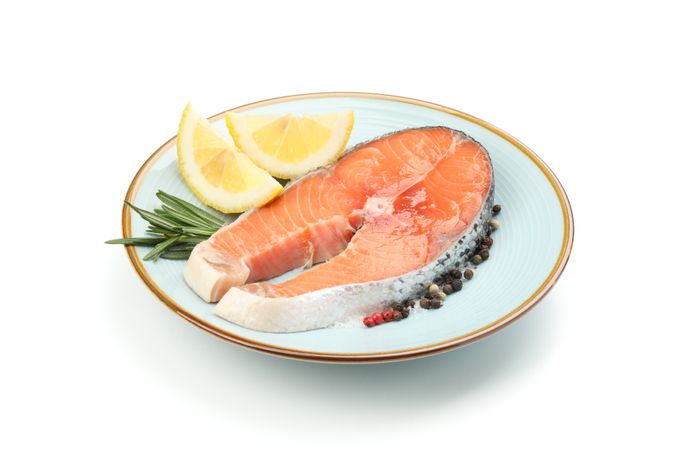 Plate with salmon meat and spices isolated on blank background