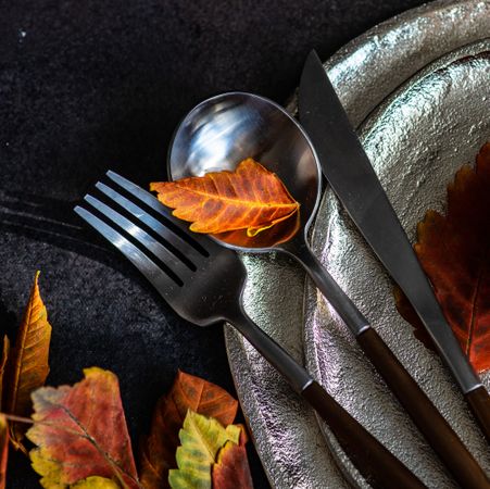 Close up of cutlery on ceramic tableware with autumn leaves