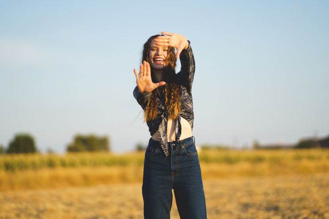 A Young Woman Playfully Posing Amidst Nature with a Beautiful Blue Sky as the Background