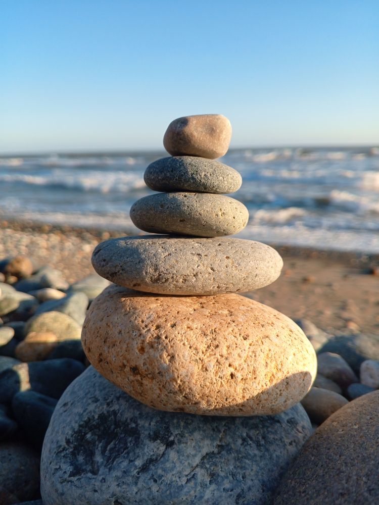 Arrangement of rocks on the beach with calm waves in the background.