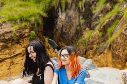 Two young female laugh and happily enjoy a day on a natural beach in summer