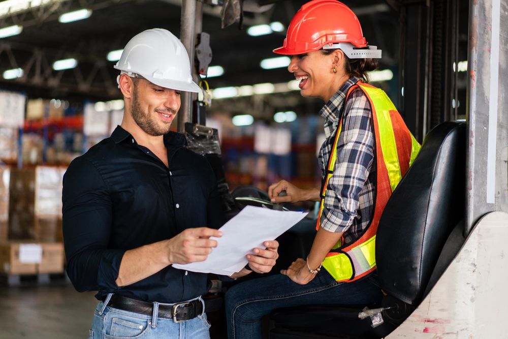 Warehouse supervisor and female forklift operator reviewing documents