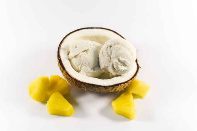 Top view of coconut shell with scoop of ice cream and pineapple fruit chunks