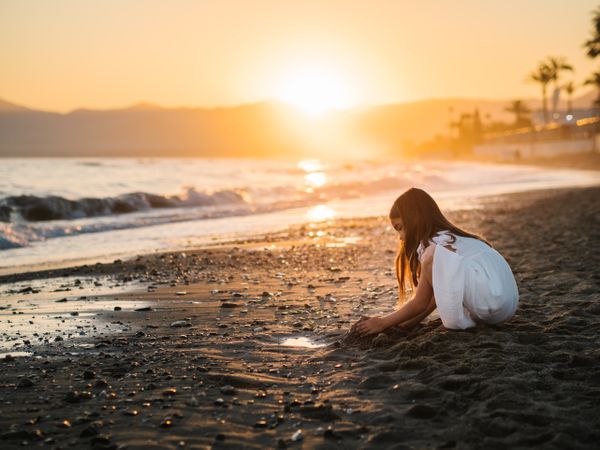 Adorable girl playing with sand on beach