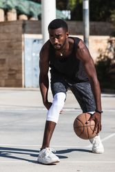 Black man playing basketball on sports ground