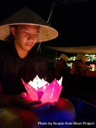 Man in conical hat holding pink lantern at night 5wKoZ5