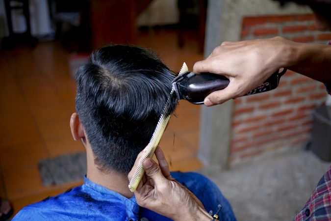 Barber cutting hair with clippers and comb
