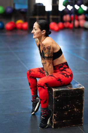 Female athlete resting sitting on a box in a gym