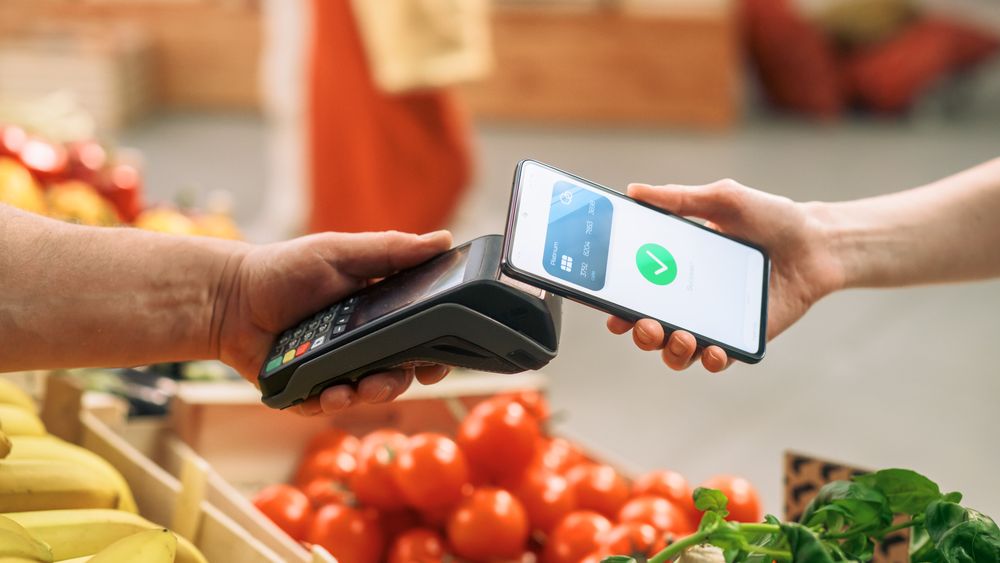 Digital Banking Concept: Shopper Using Mobile Phone with Contactless Payment Technology to Pay for Natural Goods at a Farmers Market.