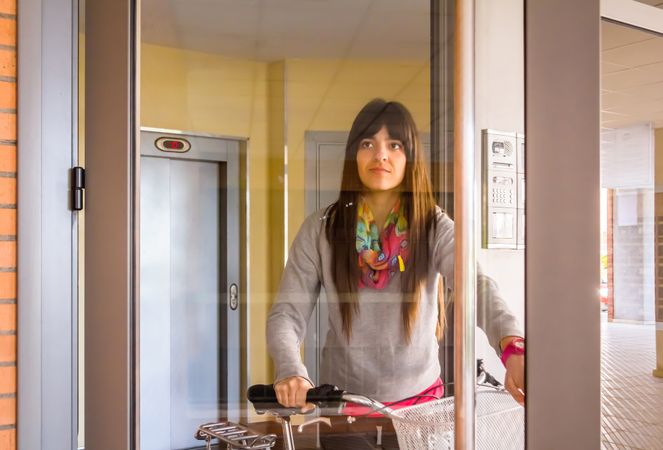 Female with fixie bike opening a glass door to exit
