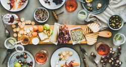 Charcuterie board with rose wine, hazelnuts, crackers, cheese, prosciutto, melon, wide composition