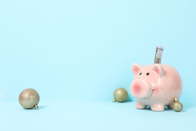 Piggy bank and New Year's balls on blue background, space for text