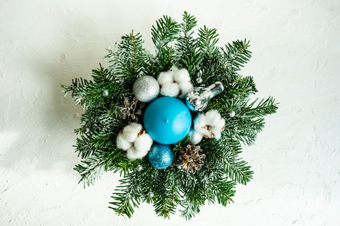 Top view of blue circular candle in the center of a decorative Christmas wreath