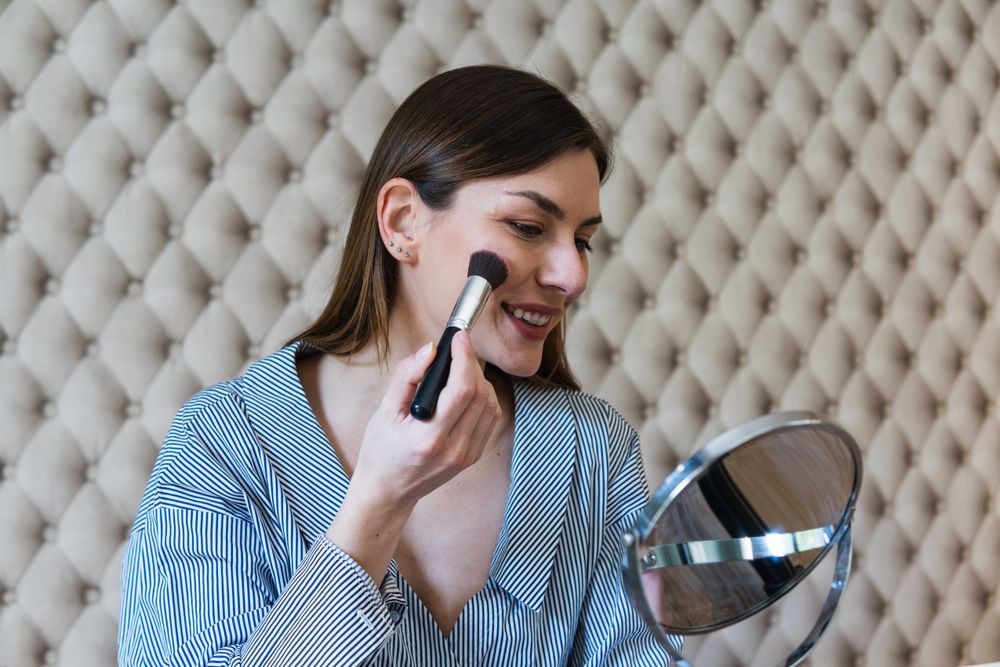 Happy woman applying powder and recording video on camera
