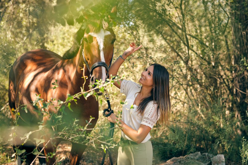 Smiling woman with horse in woodland