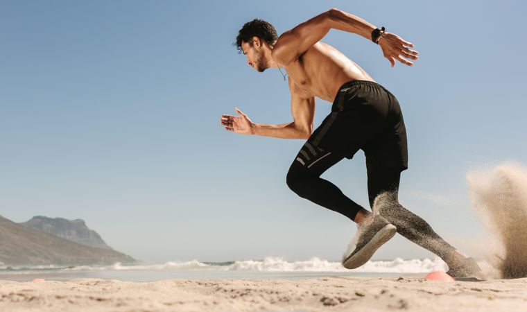 Fast runner on a beach with sand lifting off his shoes