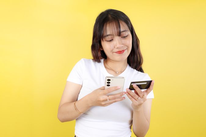Portrait of Happy Indonesian Woman Using Credit Card and Smartphone App