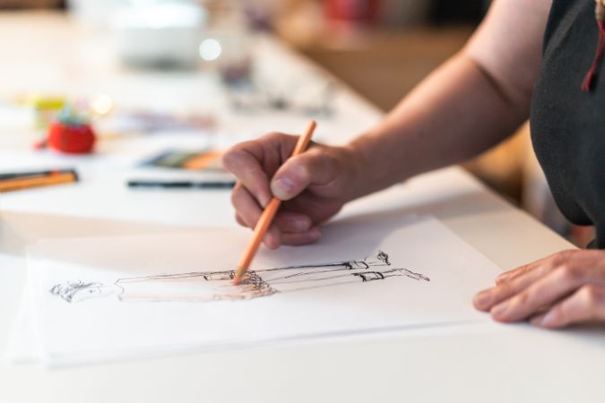 Close-up of a fashion designer drawing a fashion sketch.
