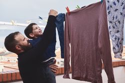 Father and son hanging clothes on rope