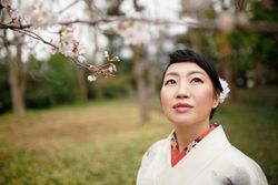 Woman in light kimono standing under cherry blossom tree