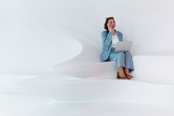 Woman with laptop talking on smartphone