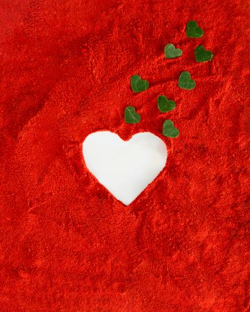 Heart shape surrounded by red soil with green leaves