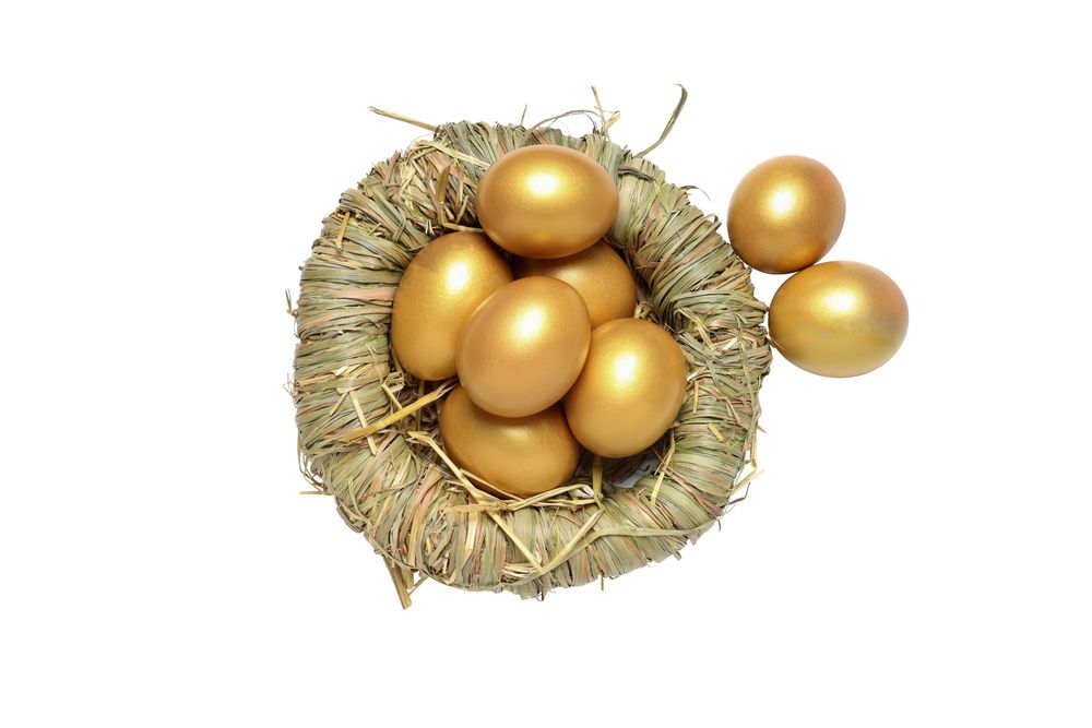 Concept of wealth and retirement - golden eggs, isolated on light background