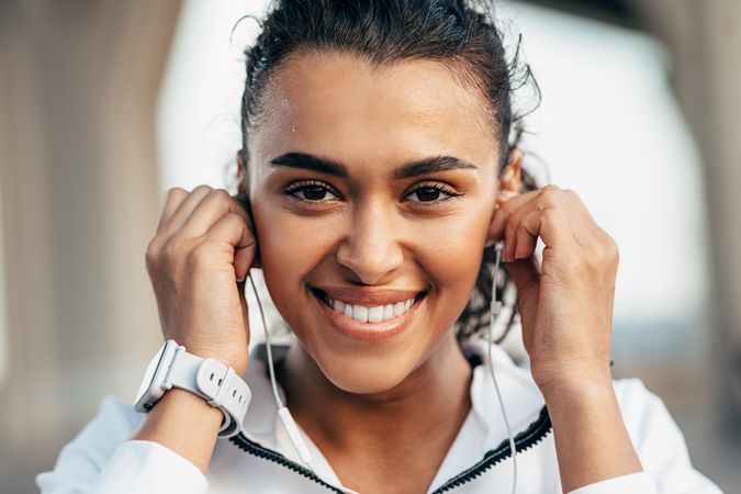 Smiling woman adducting her ear buds