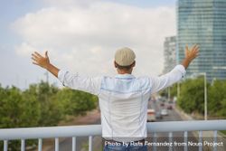 Male in denim standing with outstretched arms on bridge over city traffic 4ANkzb