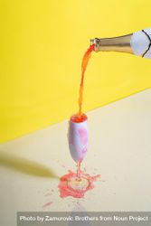 Rose champagne poured into glass against yellow background be97Pb