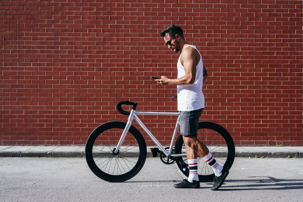 Sportive man with bicycle using phone