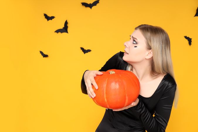 Concept of Halloween, young woman on yellow background