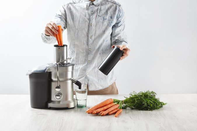 Man juicing carrots with professional equipment