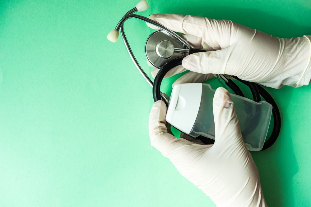 Covid-19 virus concept of hands in latex gloves holding bacterial wash and stethoscope