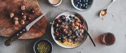 Oat granola yogurt bowl with cherries, blueberries, honey, nuts, coffee, wooden board
