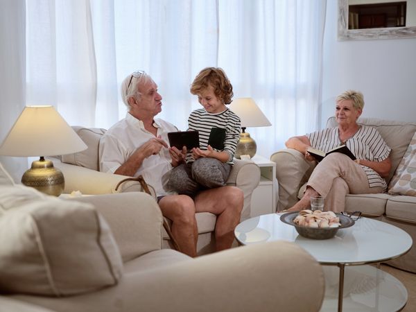 Boy browsing tablet with grandfather on couch