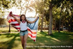 Smiling woman with American flag at park 48OOY5