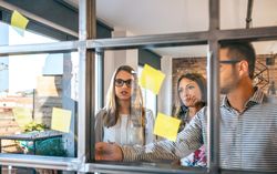 Business people in a work meeting placing sticky notes on the wall