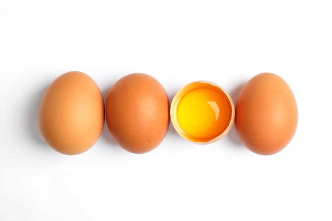 Chicken eggs and half yolk on blank background, space for text