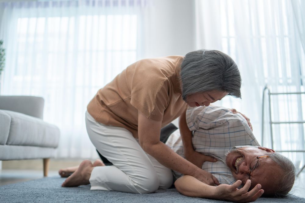 Mature male having an accident or heart attack and wife helping him at home