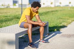 Man sitting outside looking at phone after exercising