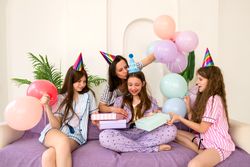 Mother placing party hat on daughter during  birthday celebration
