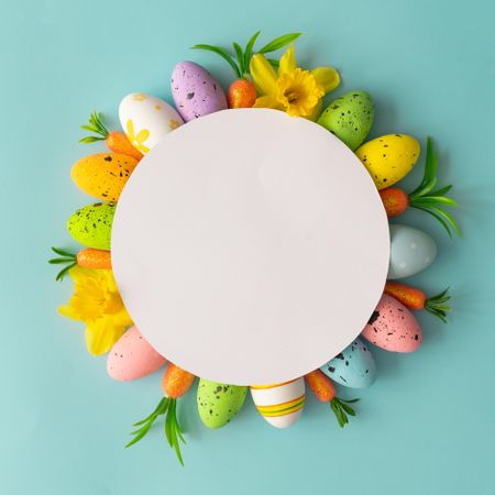 Creative composition made with colorful Easter eggs and spring flowers and paper card copy space