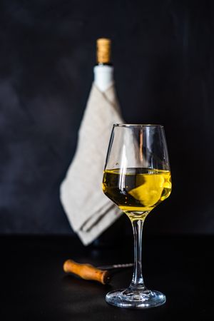 White wine glass and bottle in background