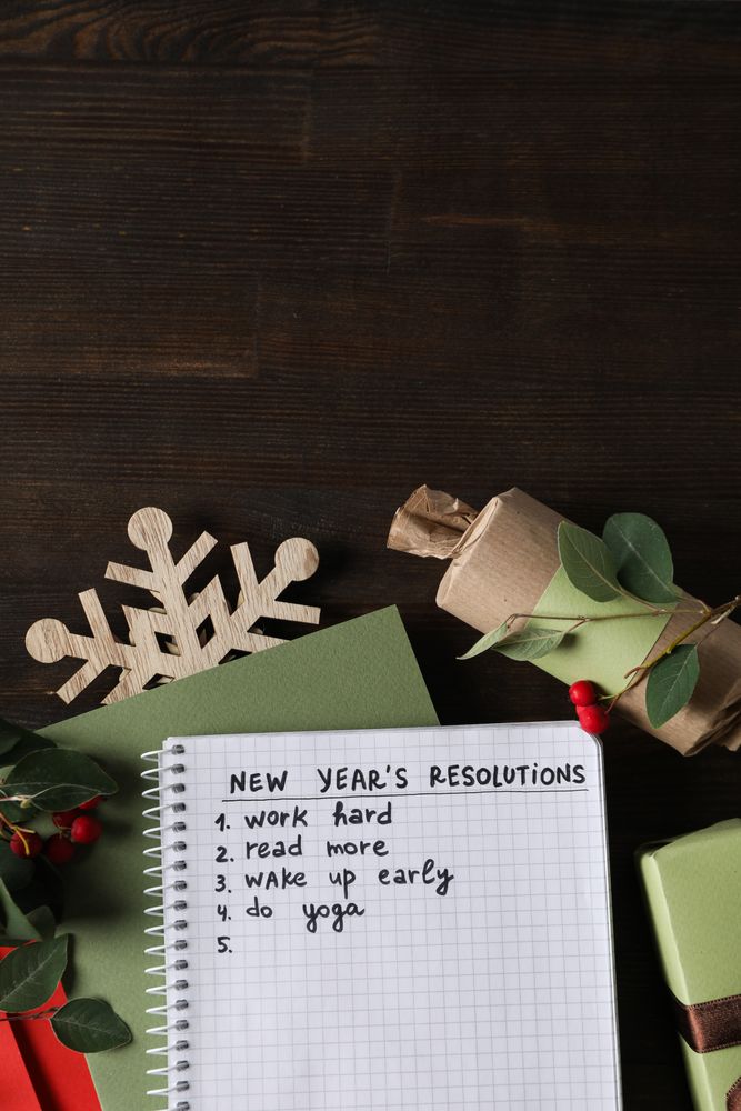 Notepad with list and decorations on wooden background, space for text