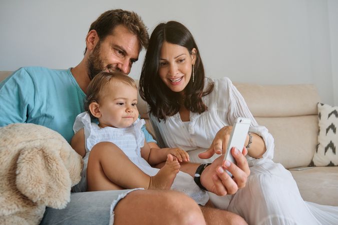 Happy family using smartphone on sofa